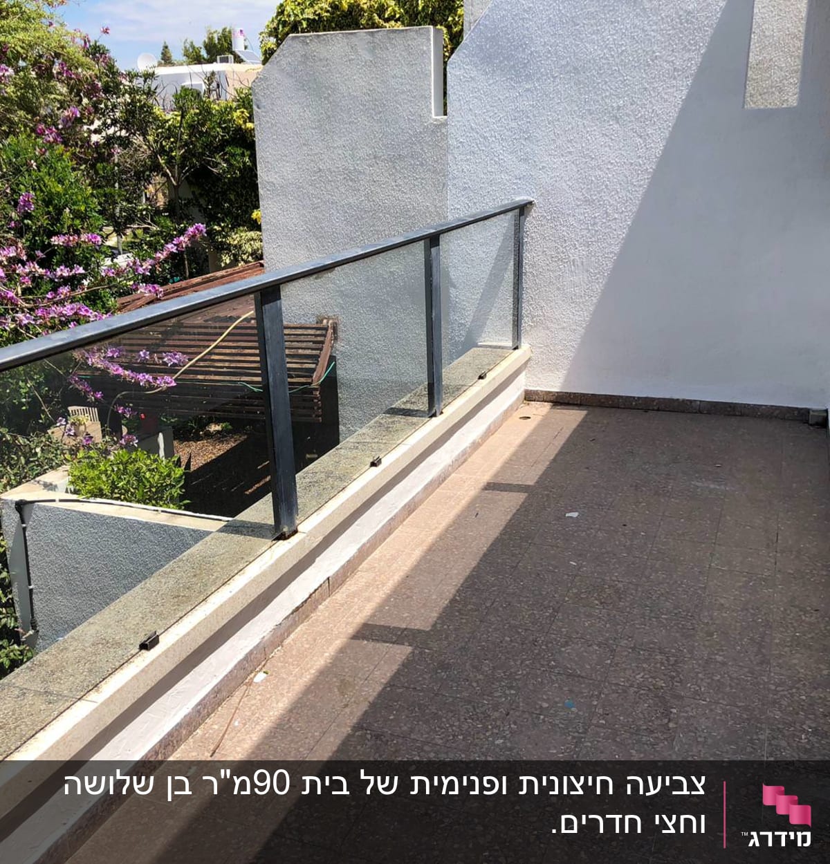 מרפסת עם מעקה זכוכית וקיר צבוע בלבן